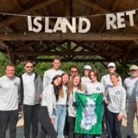 Beaver Island Participants pose in front of banner reading "Beaver Island Retreat"